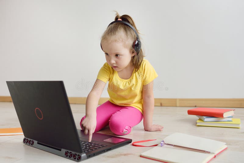 Gullig flicka som är online- på bärbara datorn Barnet sitter på internet fotografering för bildbyråer Gullig flicka som är online- på bärbara datorn Barnet sitter på internet fotografering för bildbyråer