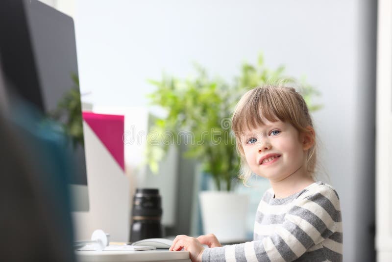 Gullig liten flicka som hemma sitter på worktablen som in camera ser royaltyfri bild Gullig liten flicka som hemma sitter på worktablen som in camera ser royaltyfri bild