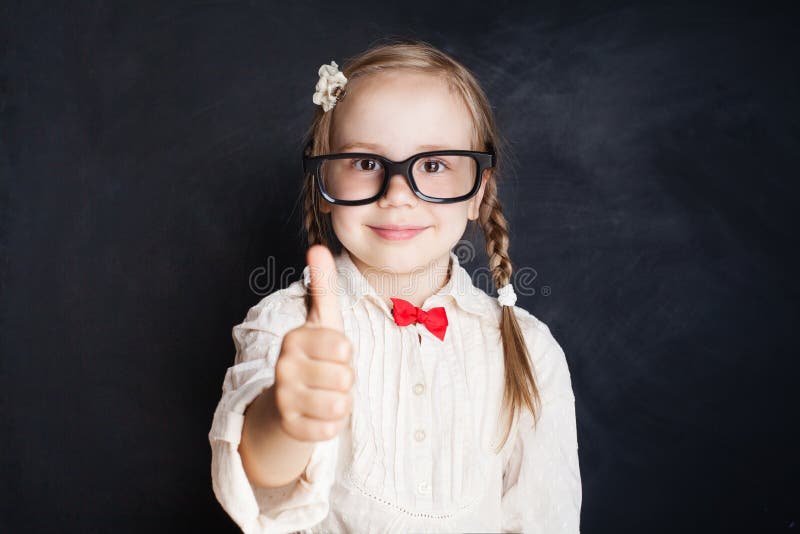 Gullig liten tumme för visning för skolaflickaelev upp arkivfoto Gullig liten tumme för visning för skolaflickaelev upp arkivfoto