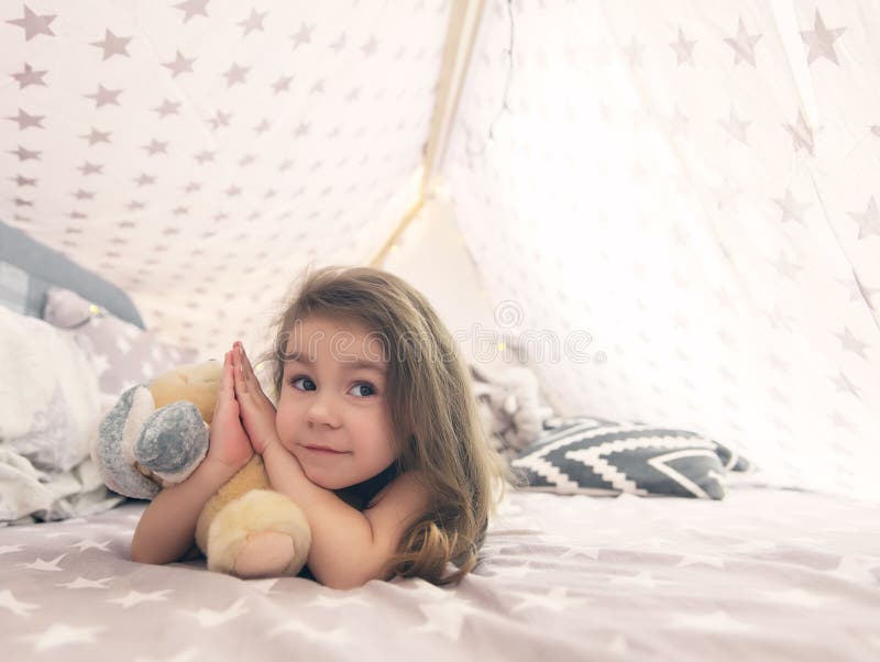 Gullig lycklig liten flicka som spelar med leksaker och drömmer i tipi och säng royaltyfria foton Gullig lycklig liten flicka som spelar med leksaker och drömmer i tipi och säng royaltyfria foton