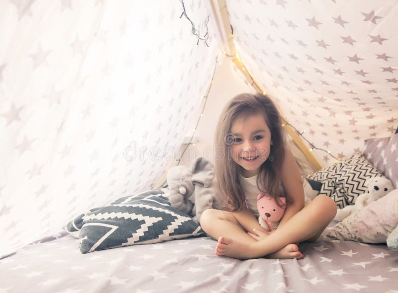 Gullig lycklig liten flicka som spelar med leksaker och drömmer i tipi och säng Slut upp fotoet av det lyckliga barnet arkivbilder Gullig lycklig liten flicka som spelar med leksaker och drömmer i tipi och säng Slut upp fotoet av det lyckliga barnet arkivbilder