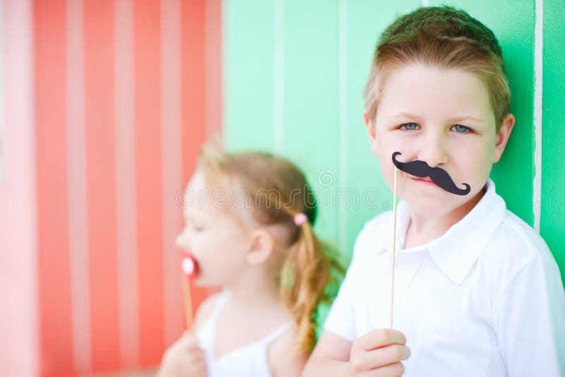 Gullig mustaschdeltagare för accessory pojke. Mustasch för holding för accessory bakgrundspojke färgrik gullig över deltagareståenden