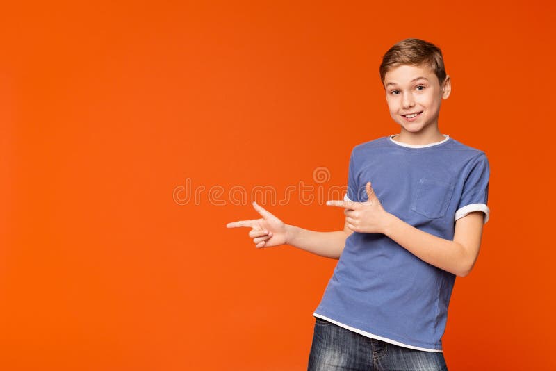 Gullig pys som pekar bort på orange bakgrund arkivfoton Gullig pys som pekar bort på orange bakgrund arkivfoton