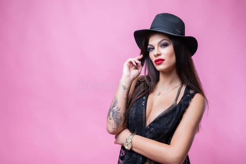 Gullig ung flicka som poserar p? rosa bakgrund i svart baddr?kt och uddar arkivfoto Gullig ung flicka som poserar p? rosa bakgrund i svart baddr?kt och uddar arkivfoto