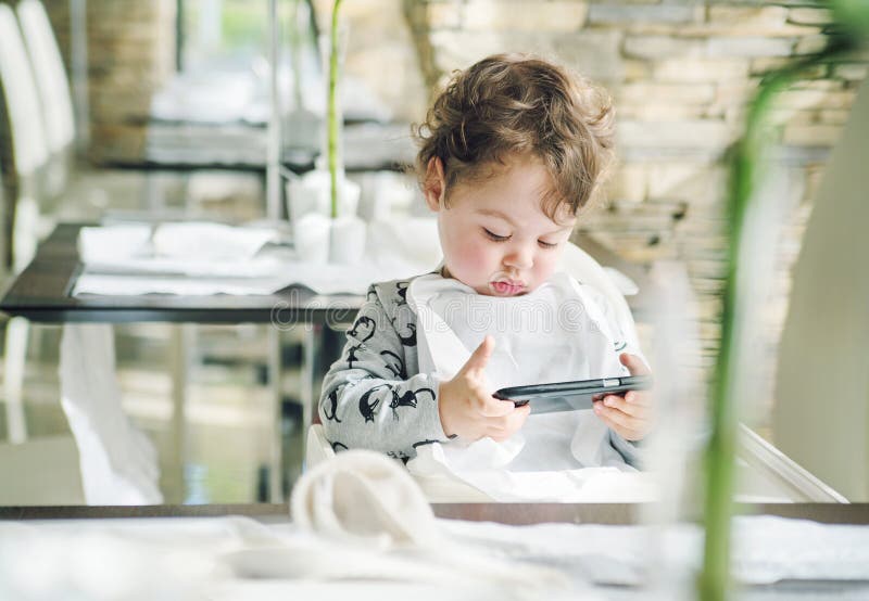 Gulligt barn som spelar lekar på med en smartphone royaltyfri bild Gulligt barn som spelar lekar på med en smartphone royaltyfri bild