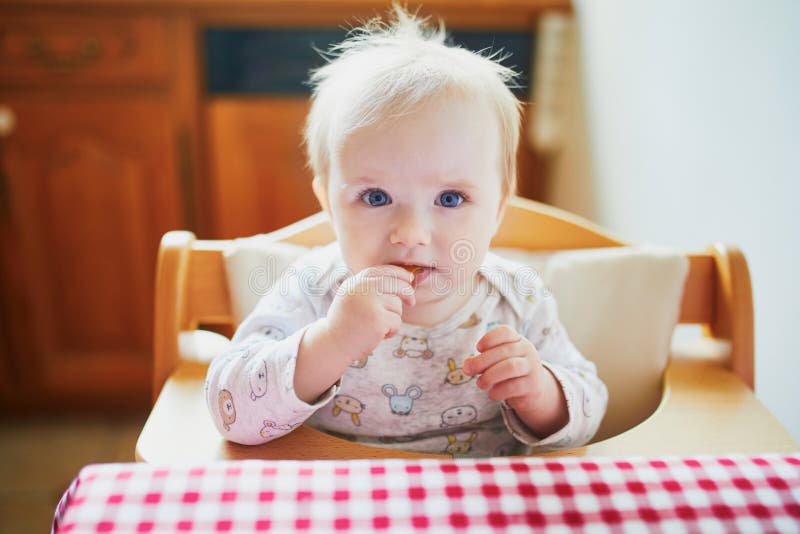 Gulligt behandla som ett barn flickan som matar sig med fingermat i köket arkivfoto