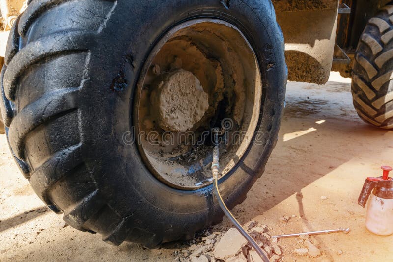 A dumper tire got a puncture and is being repaired on the building site. A dumper tire got a puncture and is being repaired on the building site