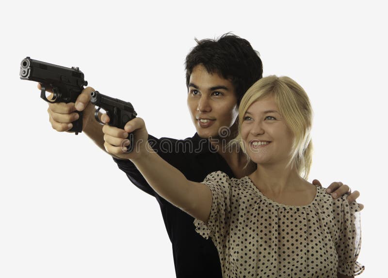 Young asian man instructs a young woman about shooting an automatic pistol. Young asian man instructs a young woman about shooting an automatic pistol