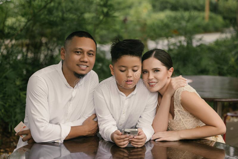 Gute internationale Familie mit asiatischem Vater mit SGD European Mom und Sohn lächeln mit Smartphone lizenzfreie stockfotografie