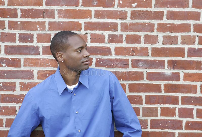 Half length portrait of one African American man against a brick wall looking off camera outdoors. Half length portrait of one African American man against a brick wall looking off camera outdoors