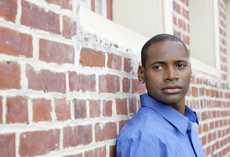 Half length portrait of one African American man against a brick wall looking off camera outdoors. Half length portrait of one African American man against a brick wall looking off camera outdoors
