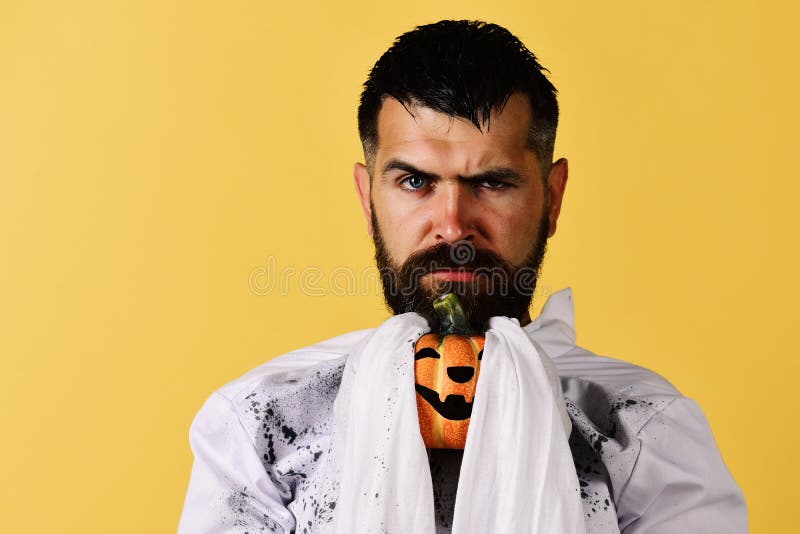 Guy with beard holds orange pumpkin. Halloween and happy holiday. Concept. Halloween character in white long sleeved ghost costume. Man with serious face stock photos Guy with beard holds orange pumpkin. Halloween and happy holiday. Concept. Halloween character in white long sleeved ghost costume. Man with serious face stock photos