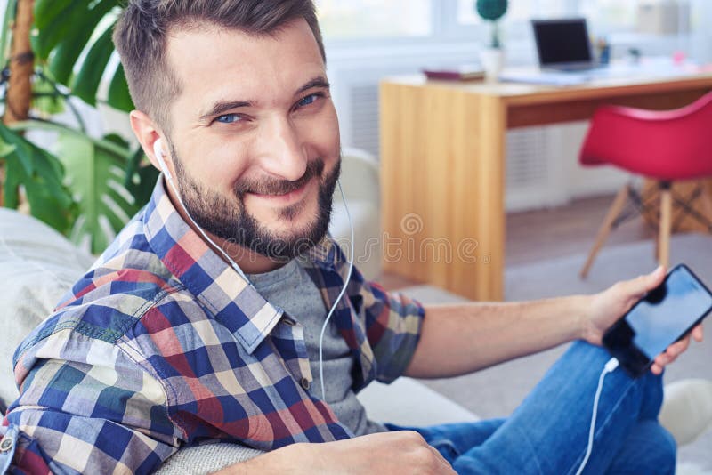 Guy with beautiful blue eyes listening to music with headphones