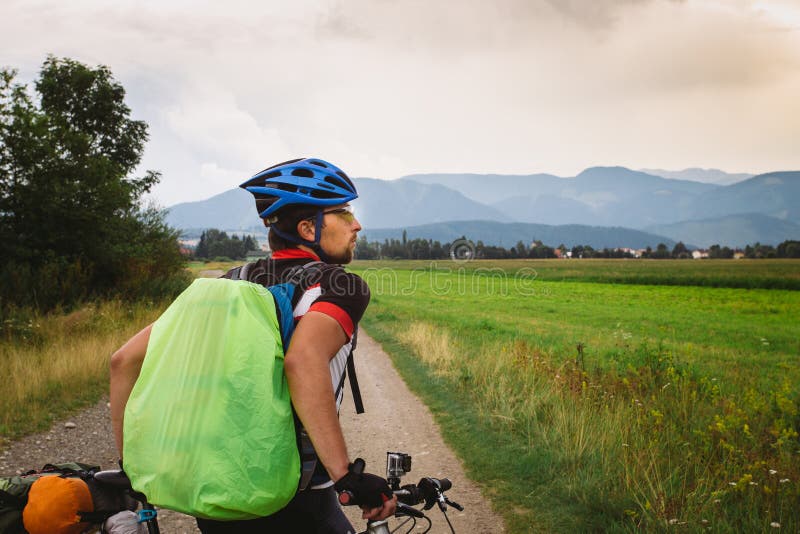 The guy on the Bicycle travels in Slovakia. Blue helmet, green backpack, glasses,