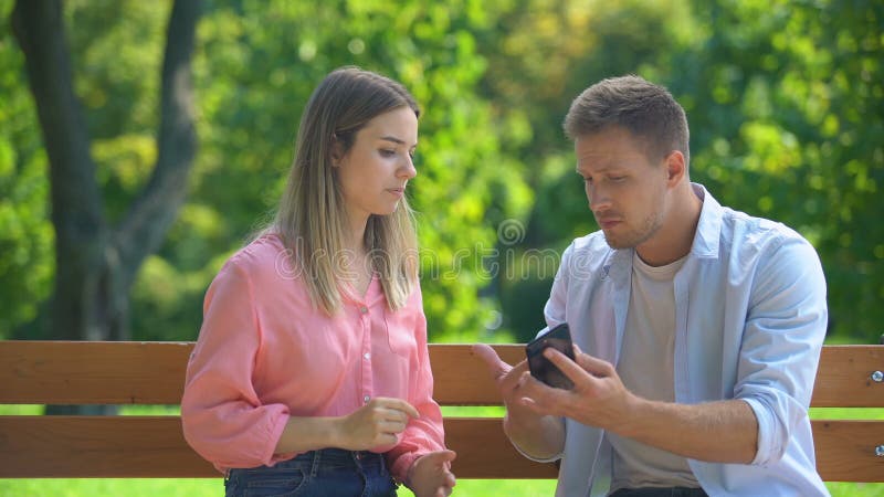 Guy checking girlfriends phone asking about chats with other men, jealousy