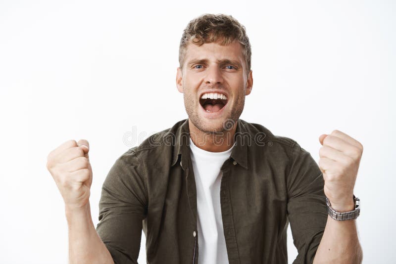 Guy cheering with excitement and joy yelling at camera supportive words clenching fists in joy and, being assertive boosting confidence, encourage friend to take action posing over gray background. Emotions and body language concept