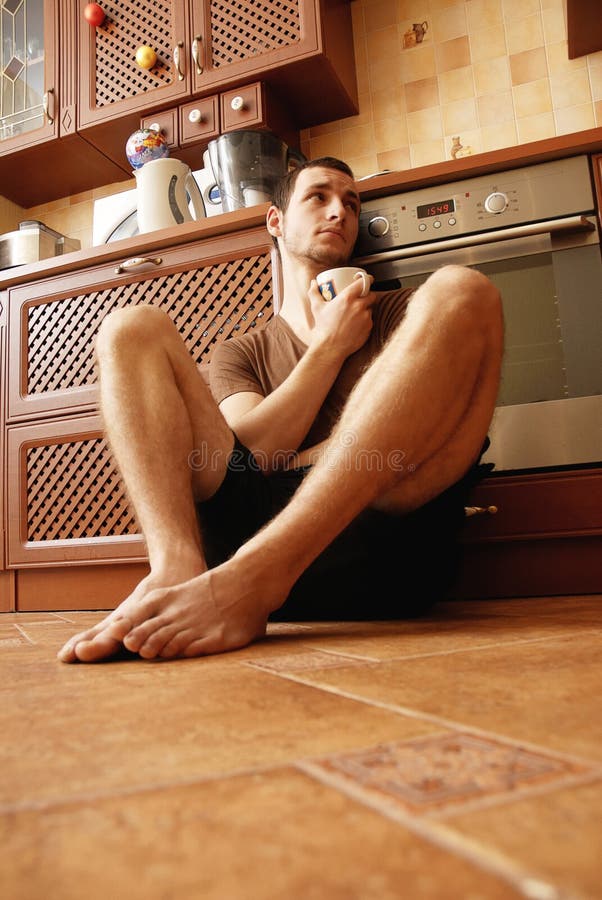 Guy on the floor in the kitchen with cup of tea