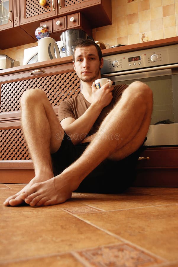 Guy on the floor in the kitchen with cup of tea