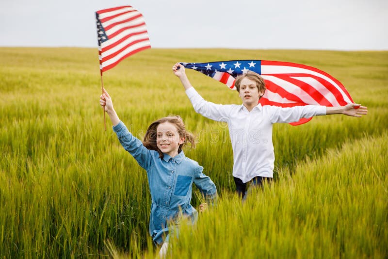 Guy and girl running in a field with an American flag in their hands