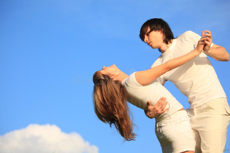 Guy holds girl against sky