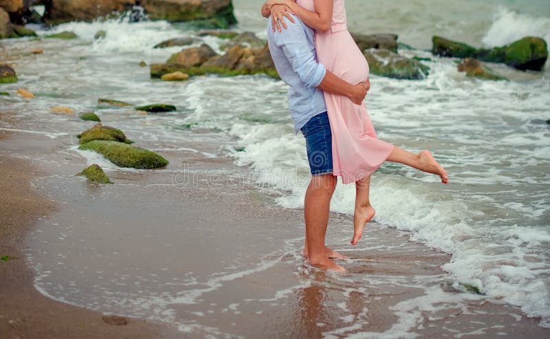 A Man Holds A Woman With Her Legs Engulfing His Waist And She Laughs  Joyfully Towards The Ocean. High Quality Photo Stock Photo, Picture and  Royalty Free Image. Image 164446145.