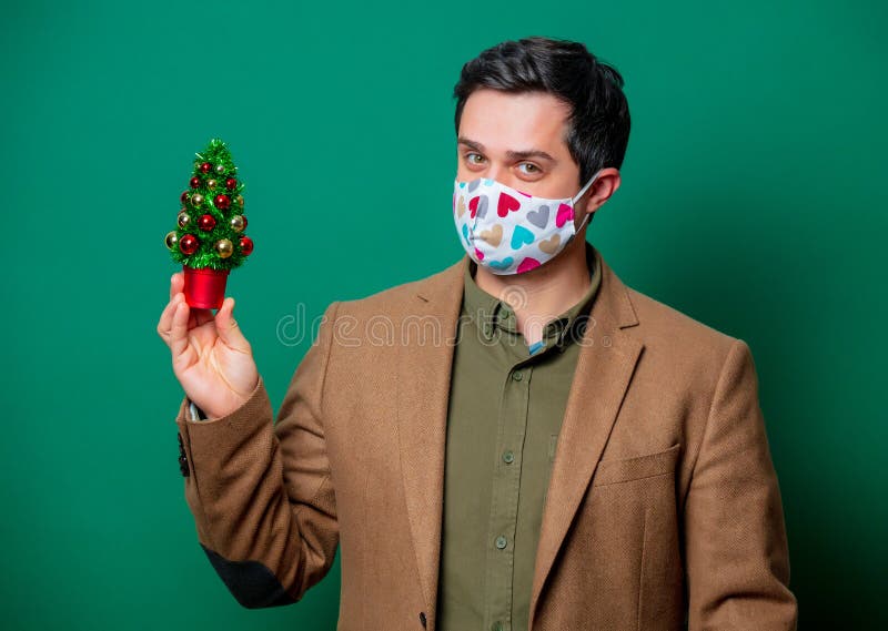 Guy in jacket and face mask hold Christmas tree royalty free stock images