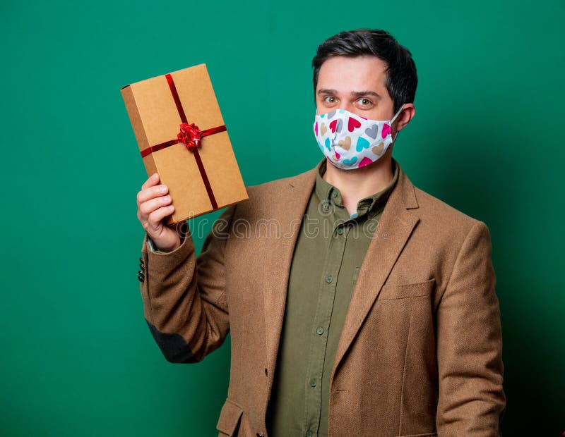 Guy in jacket and face mask hold gift box royalty free stock image