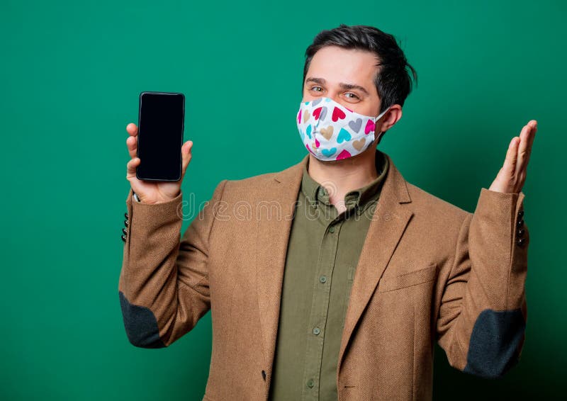 Guy in jacket and face mask hold mobile phone stock image