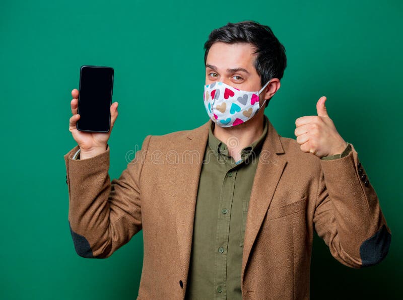 Guy in jacket and face mask hold mobile phone stock photos