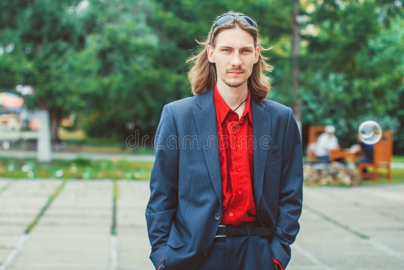 The guy in the jacket with long hair. A man with long hair in buisness stock photo