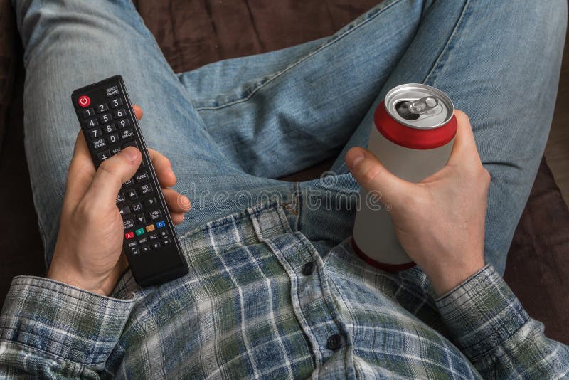 Guy is lying on sofa with TV remote control and drinking beer royalty free stock image Guy is lying on sofa with TV remote control and drinking beer royalty free stock image