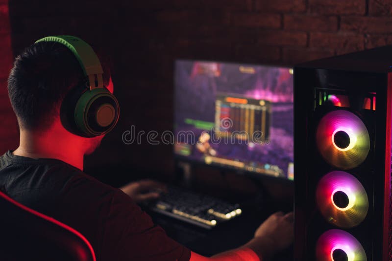 Guy Playing Video Games on Computer Under Red Neon Light Stock Image