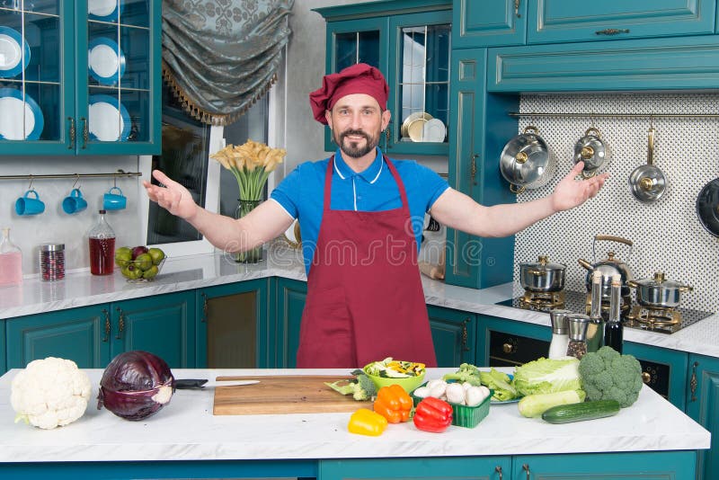 Guy welcomes to kitchen. Handsome cook invites to cooking vegetables. Man0prepared vegetables for cooking with love. stock photos Guy welcomes to kitchen. Handsome cook invites to cooking vegetables. Man0prepared vegetables for cooking with love. stock photos