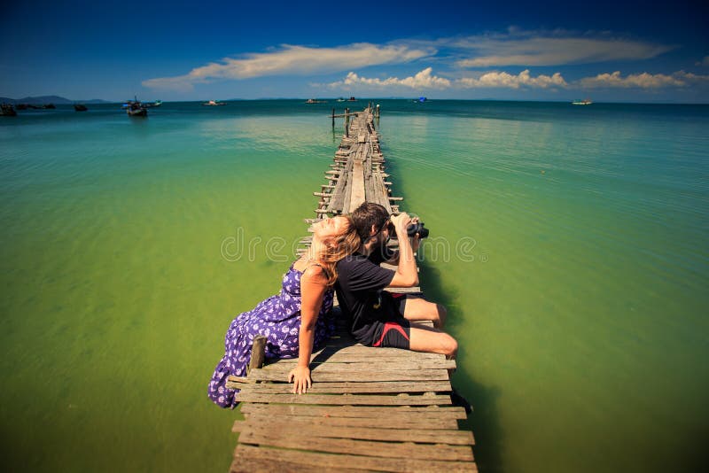 Guy Takes Photo Girl Sits op Pijler tegen Oceaan royalty-vrije stock foto's Guy Takes Photo Girl Sits op Pijler tegen Oceaan royalty-vrije stock foto's