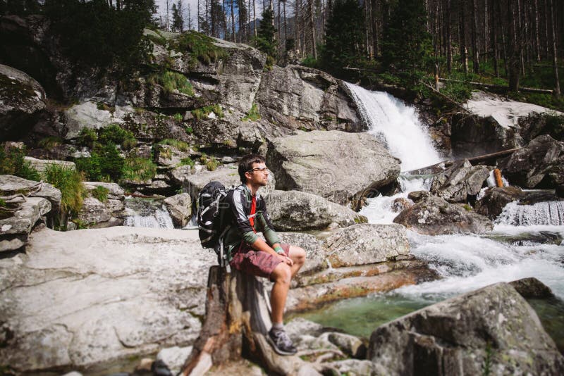 The guy was a tourist with sitting on a rock near the waterfall in Slovakia