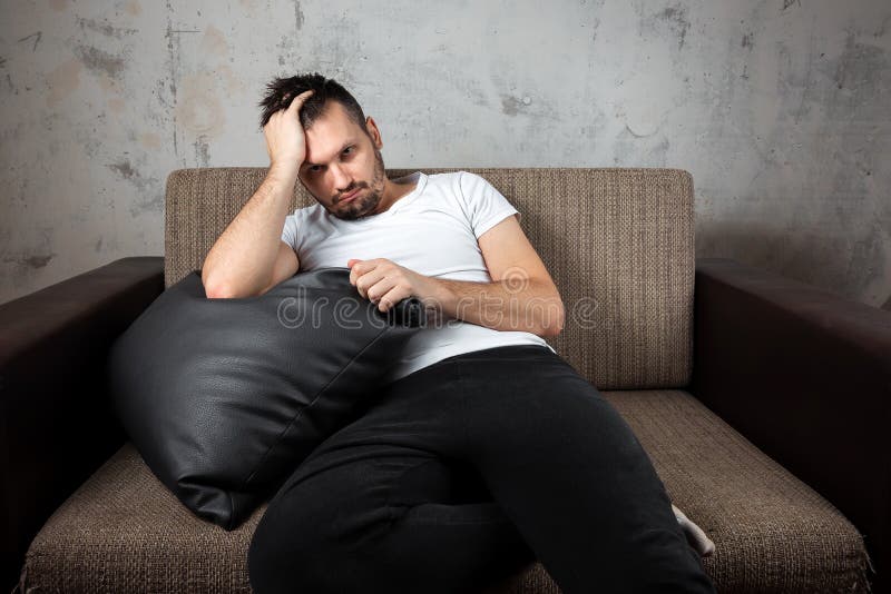 The guy in the white shirt is lying on the couch. The concept of laziness, apathy, frustration, procrastination