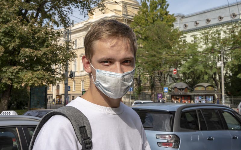 A guy 20-25 years old in a medical mask against the background of a European city. Concept: studying in Europe, the beginning of t royalty free stock images A guy 20-25 years old in a medical mask against the background of a European city. Concept: studying in Europe, the beginning of t royalty free stock images