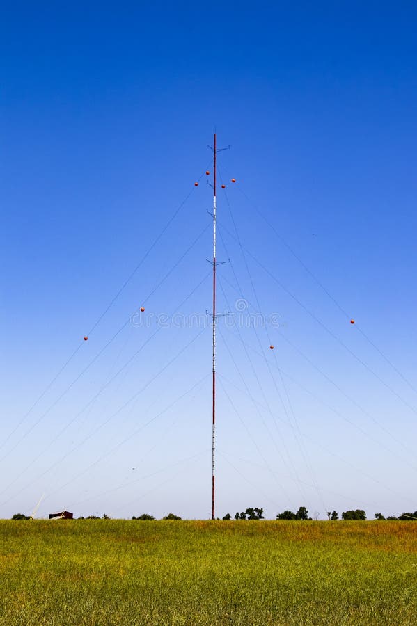 Guyed radia el radiador del palo para las telecomunicaciones y la difusión con los aisladores rojos de la porcelana en los alambr foto de archivo libre de regalías Guyed radia el radiador del palo para las telecomunicaciones y la difusión con los aisladores rojos de la porcelana en los alambr foto de archivo libre de regalías