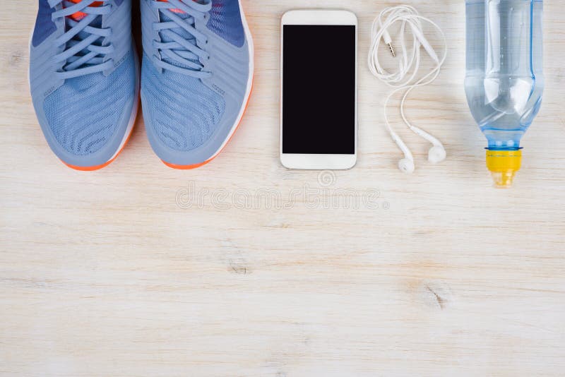 Gymnastikskor, smartphone och vatten på trä med copyspace i botten arkivfoton Gymnastikskor, smartphone och vatten på trä med copyspace i botten arkivfoton