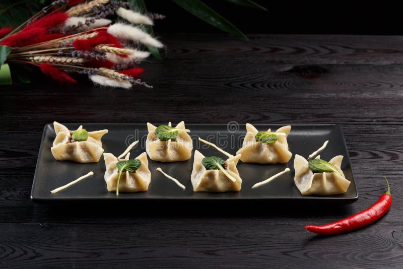 Gyoza com espinafres, ricota e cordeiro em uma placa preta em um fundo de madeira escuro imagens de stock Gyoza com espinafres, ricota e cordeiro em uma placa preta em um fundo de madeira escuro imagens de stock