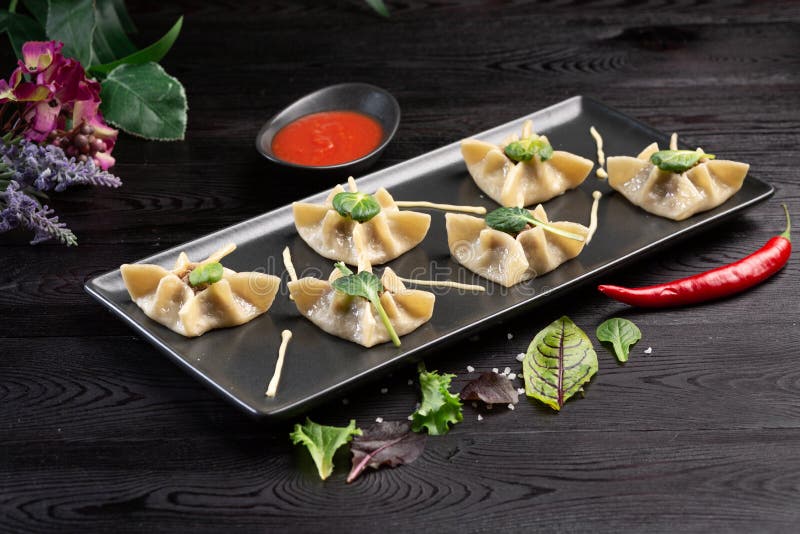 Gyoza med spenat, ricotta och lammet p? en svart platta p? en m?rk tr?bakgrund royaltyfria bilder Gyoza med spenat, ricotta och lammet p? en svart platta p? en m?rk tr?bakgrund royaltyfria bilder