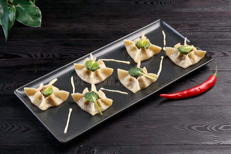 Gyoza με το σπανάκι, το ricotta και το αρνί σε ένα μαύρο πιάτο σε ένα σκοτεινό ξύλινο υπόβαθρο στοκ φωτογραφίες με δικαίωμα ελεύθερης χρήσης Gyoza με το σπανάκι, το ricotta και το αρνί σε ένα μαύρο πιάτο σε ένα σκοτεινό ξύλινο υπόβαθρο στοκ φωτογραφίες με δικαίωμα ελεύθερης χρήσης