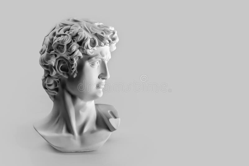 Gypsum statue of David`s head. Michelangelo`s David statue plaster copy on grey background with copyspace for text. Ancient greek sculpture, statue of hero