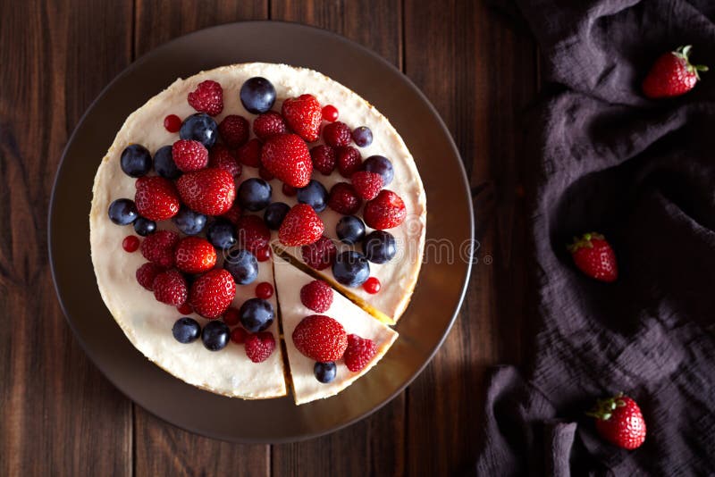 Close up. Delicious Homemade creamy mascarpone New York Cheesecake with berries on dark wooden table. Top viev. Close up. Delicious Homemade creamy mascarpone New York Cheesecake with berries on dark wooden table. Top viev.