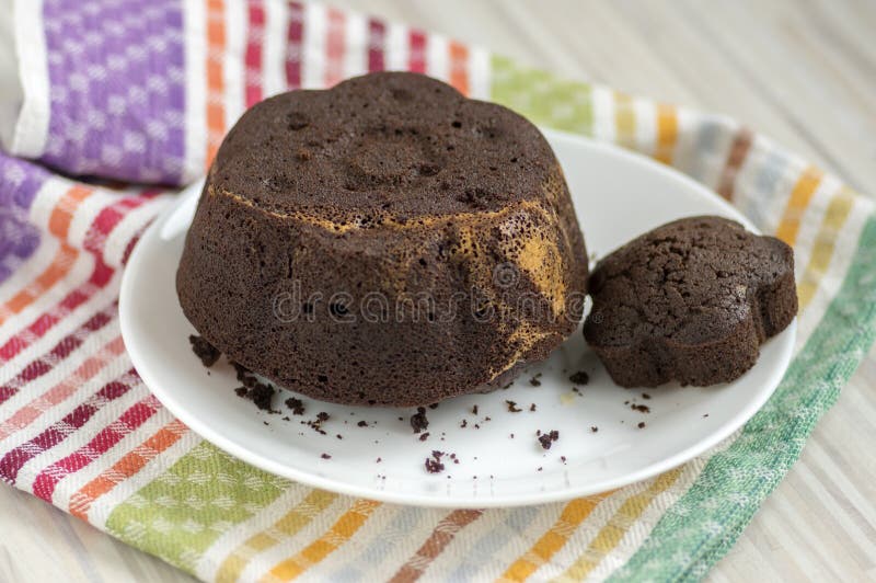 Gâteau de chocolat du plat blanc sur la serviette de cuisine colorée, biscuit brun foncé doux savoureux photographie stock libre de droits Gâteau de chocolat du plat blanc sur la serviette de cuisine colorée, biscuit brun foncé doux savoureux photographie stock libre de droits