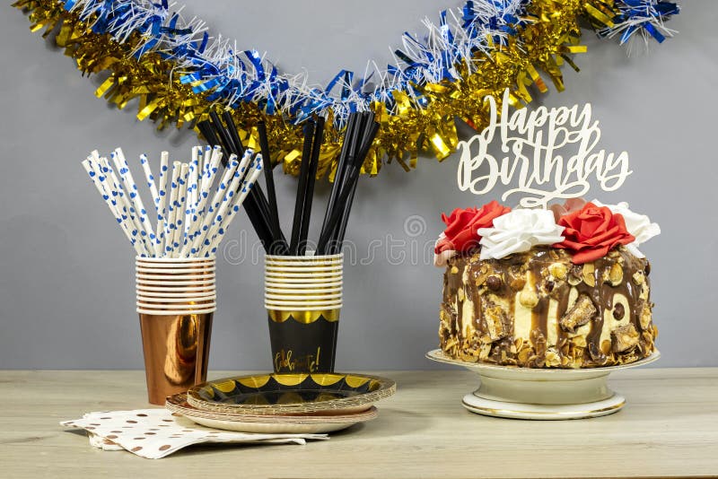 Gâteau de couche d'anniversaire décoré de morceaux de chocolat et texte d'anniversaire heureux noisettes et fleurs de roses dans l