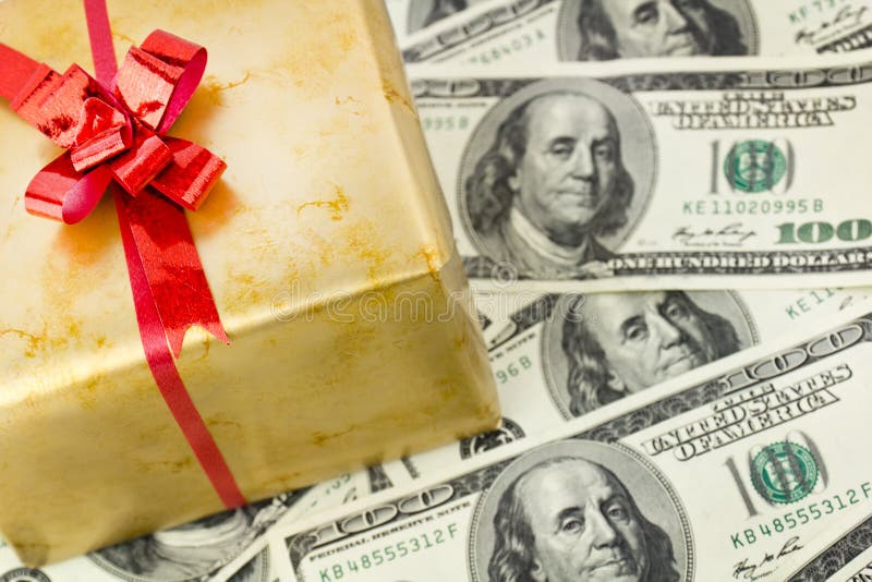 Golden gift box with red ribbon on hundred dollars bilsl. Holiday concept background. Golden gift box with red ribbon on hundred dollars bilsl. Holiday concept background