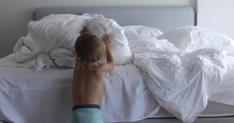 Gör en säng, barnet som gör upp hennes säng i rum efter vak