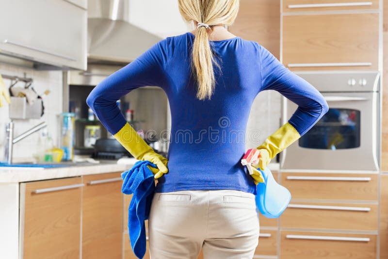 Rear view of woman with yellow gloves in kitchen doing housework. Rear view of woman with yellow gloves in kitchen doing housework