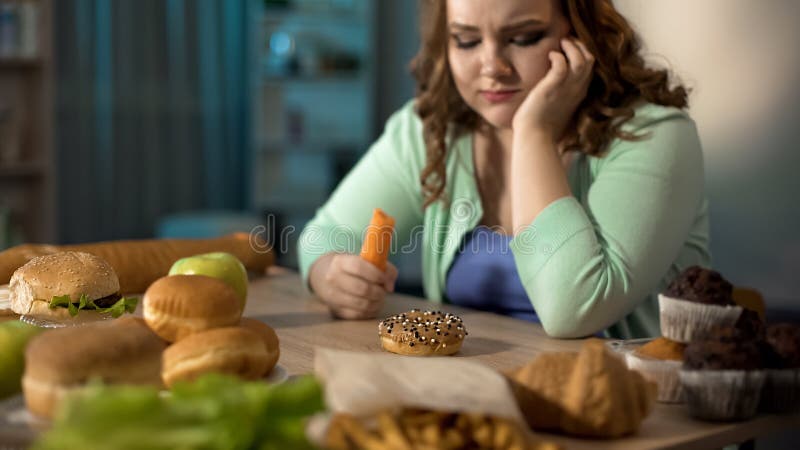 Głodna gruba damy łasowania marchewka, marzący o pączku i fascie food, zdrowa dieta zdjęcie royalty free Głodna gruba damy łasowania marchewka, marzący o pączku i fascie food, zdrowa dieta zdjęcie royalty free